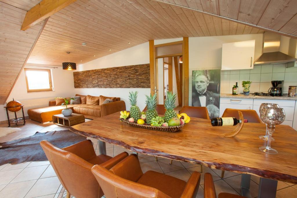 cocina y sala de estar con mesa de madera y sillas en Residenz Cheval am Pfaffenberg Friedrichshafen Messe, en Oberteuringen