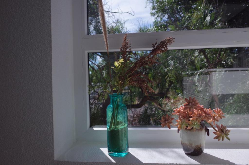a green vase sitting on a window sill with flowers at Lei Home in Cascais