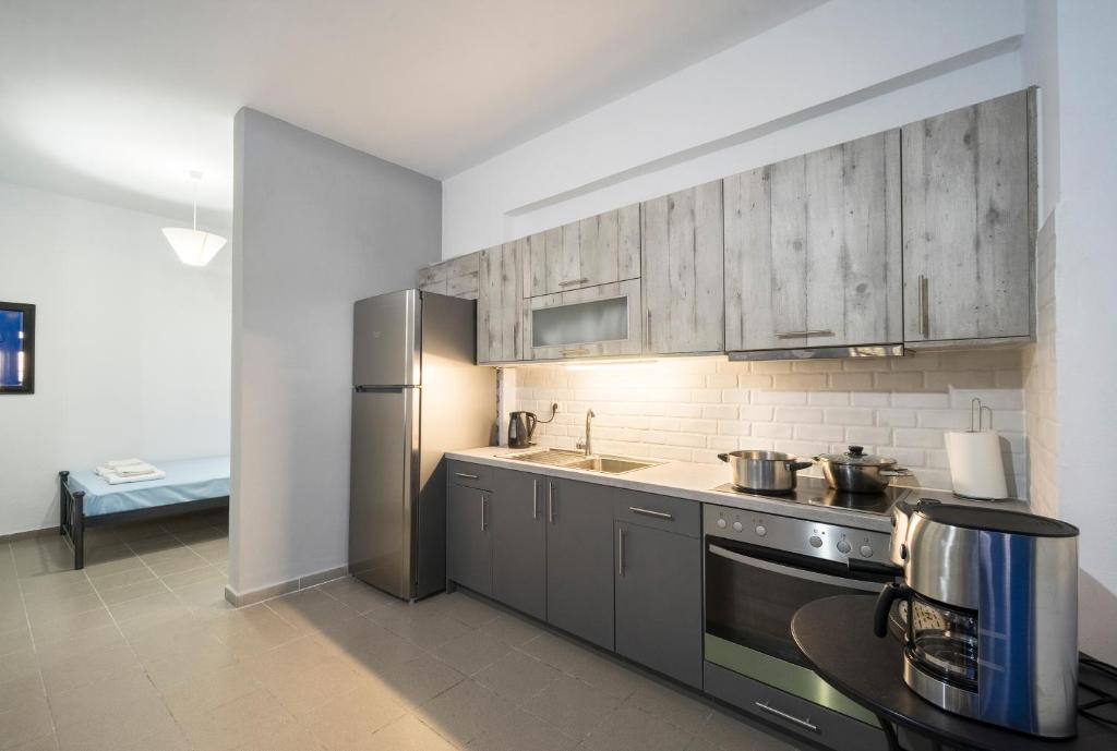 a kitchen with gray cabinets and a stainless steel refrigerator at Sunset Home Crete in Paránimfoi