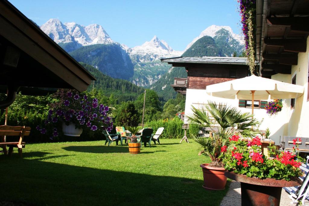 un jardín con sillas, sombrilla y montañas en Apartments Landhaus Sonnheim, en Lofer