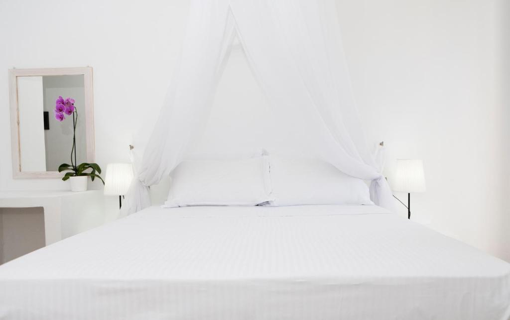 1 cama blanca con almohadas blancas y espejo en Harmony Hotel, en Sarandë