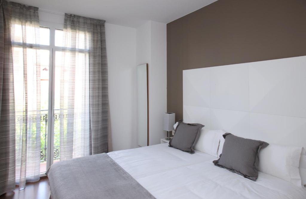 a bedroom with a white bed and a large window at MH Apartments Suites in Barcelona