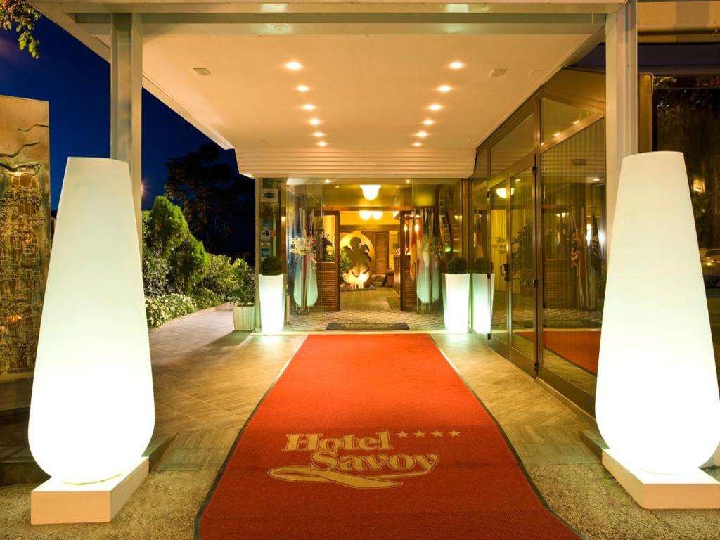 un hall d'entrée avec un tapis rouge devant un bâtiment dans l'établissement Hotel Savoy, à Pesaro