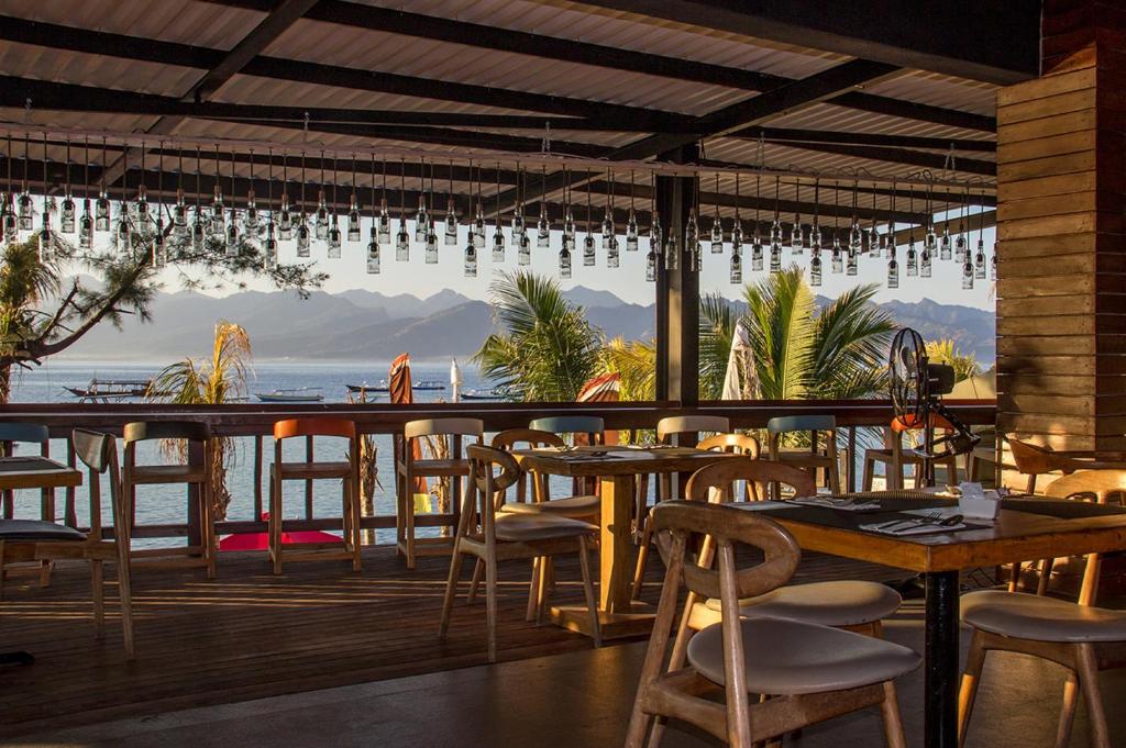 a restaurant with tables and chairs and a view of the ocean at Natya Hotel Gili Trawangan in Gili Trawangan