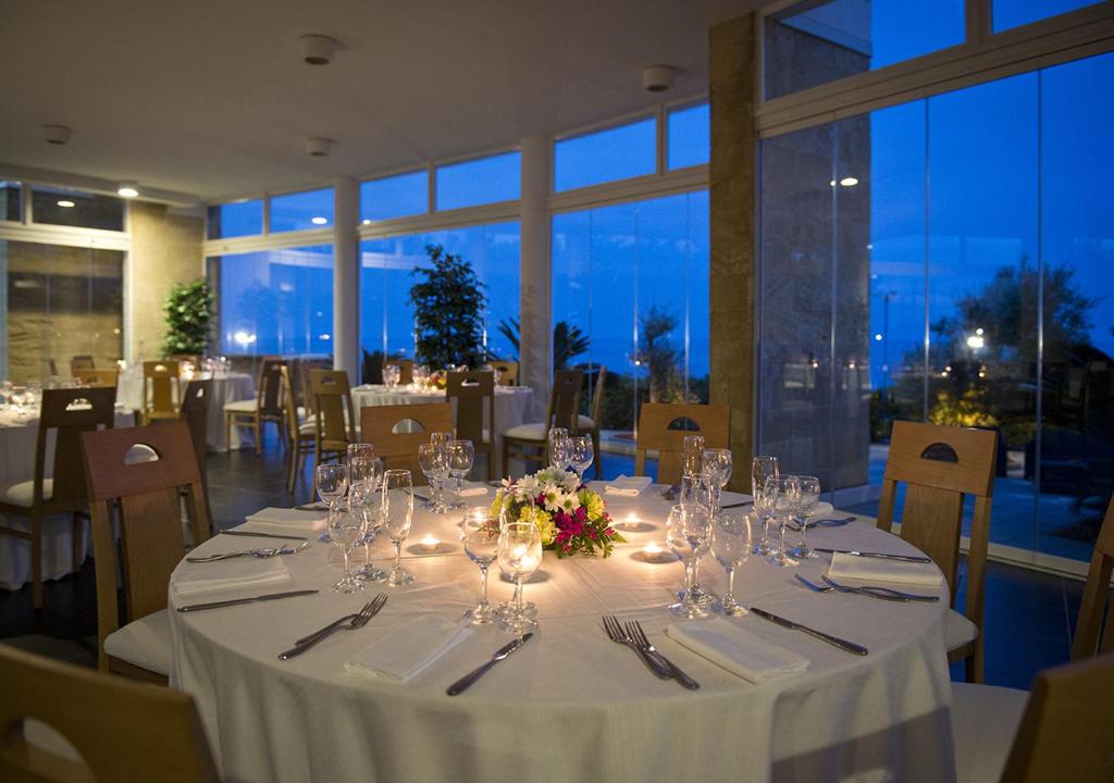 a dining room with a table with wine glasses and flowers at Corvino Resort in Monopoli