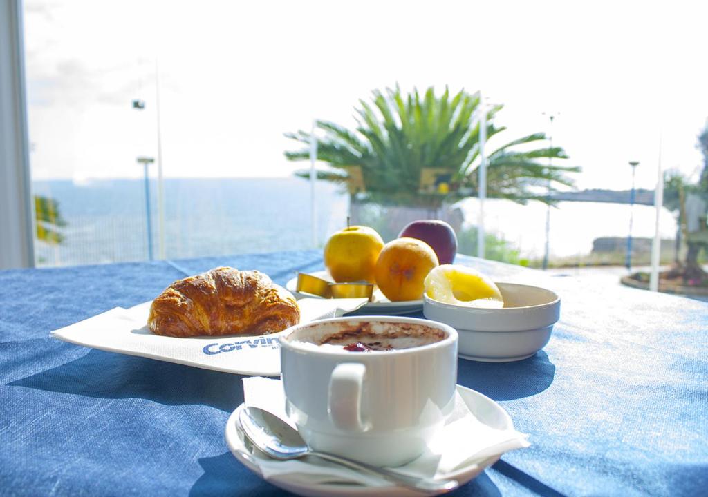 a table with a cup of coffee and a plate of food at Corvino Resort in Monopoli