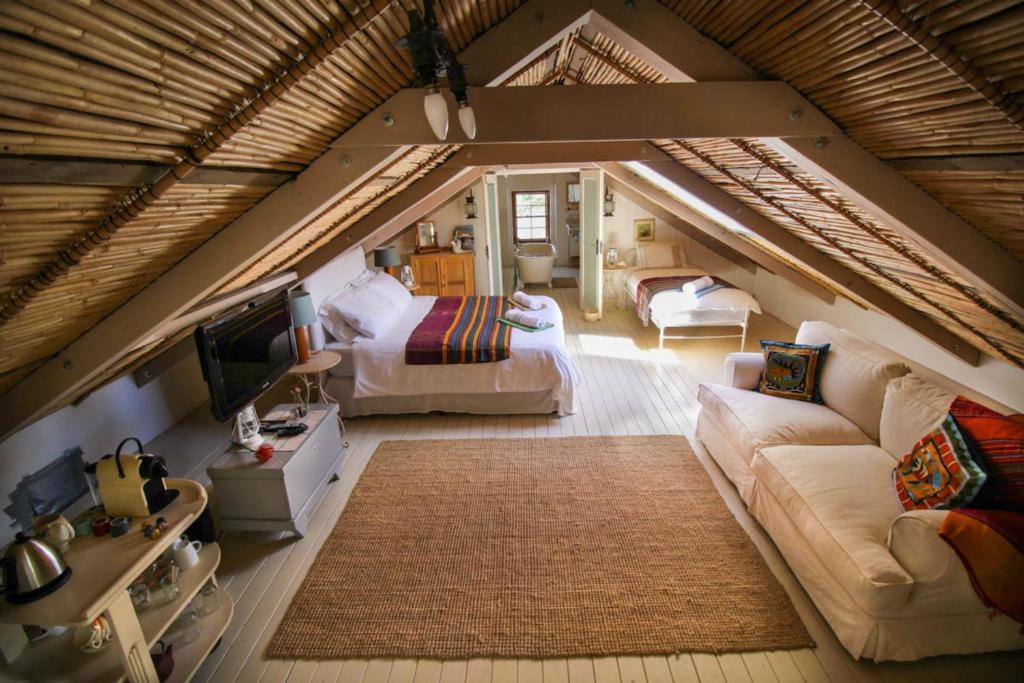 a large attic room with a bed and a couch at The Luxury Loft in Montagu