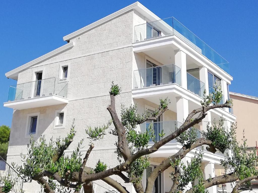 a white building with a tree in front of it at Villa Perla Dalmatica in Rogoznica