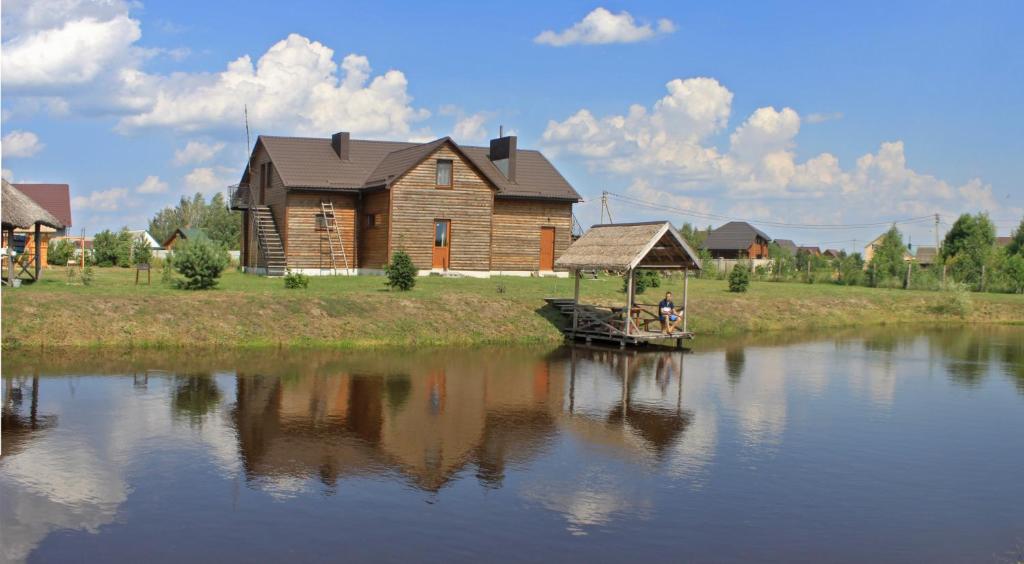 una casa de madera y un barco en un río en Cisarska sadyba, en Svityazʼ