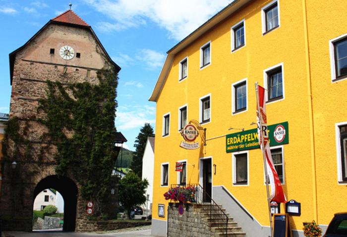 ein gelbes Gebäude mit einem Uhrturm daneben. in der Unterkunft Gasthof 'Zum alten Turm' in Haslach an der Mühl