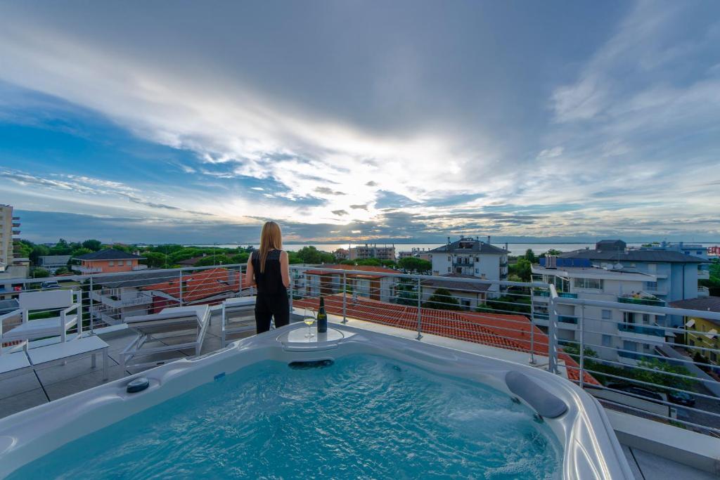 Soleis Sea View Spa Apartment في لينانو سابيادورو: امرأة تقف في حوض استحمام ساخن على شرفة