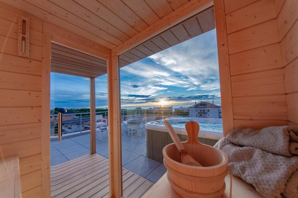 a room with a balcony with a view of the ocean at Aurea Attico con Jacuzzi e vista mare Lignano in Lignano Sabbiadoro