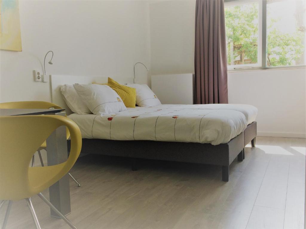 een slaapkamer met een bed met witte lakens en gele kussens bij Haarlem 49 in Haarlem