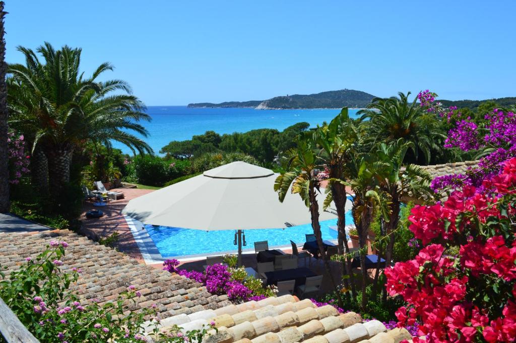 a swimming pool with a white umbrella and flowers at Residence Fenicia in Villasimius