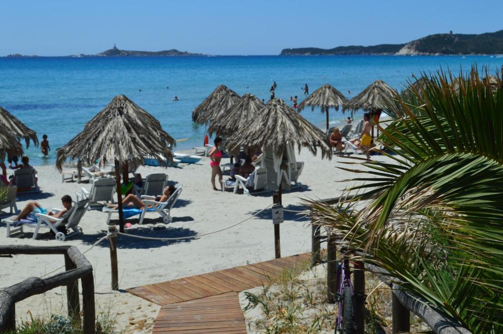people on a beach with umbrellas and the ocean at Residence Fenicia in Villasimius