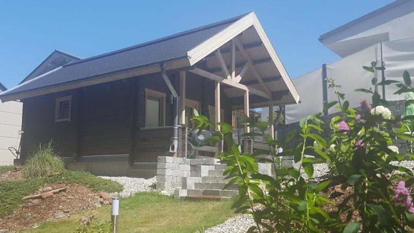 a small black house with a porch and some flowers at Sabine's Wellnesslodge in Ruppertsweiler