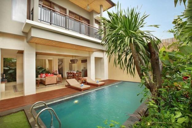 a swimming pool in front of a house at Kamajaya Villas in Ubud