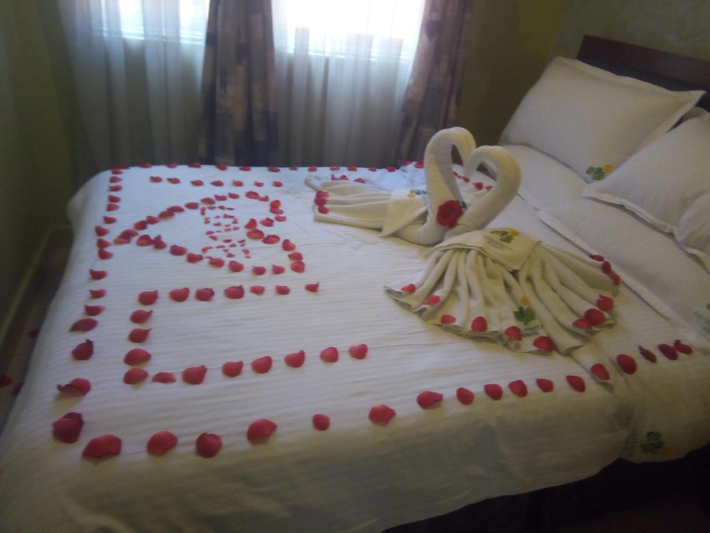 a cake with swans on a bed with roses at Ash White Hotel in Nairobi