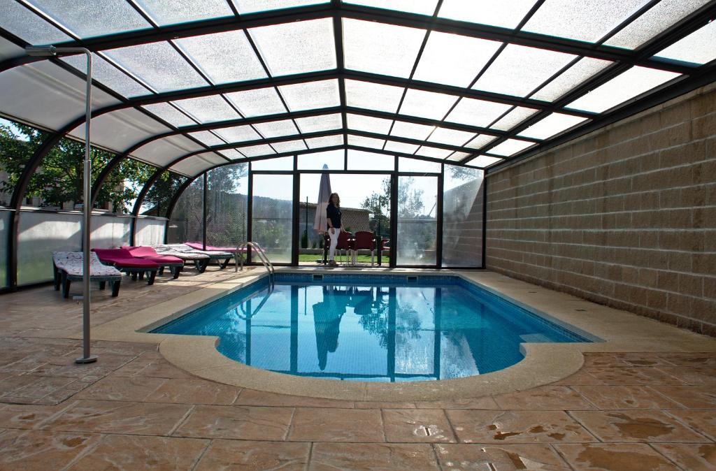 a swimming pool with a glass ceiling and a woman standing in front of it at casa oliva la bodegueta in Abiego