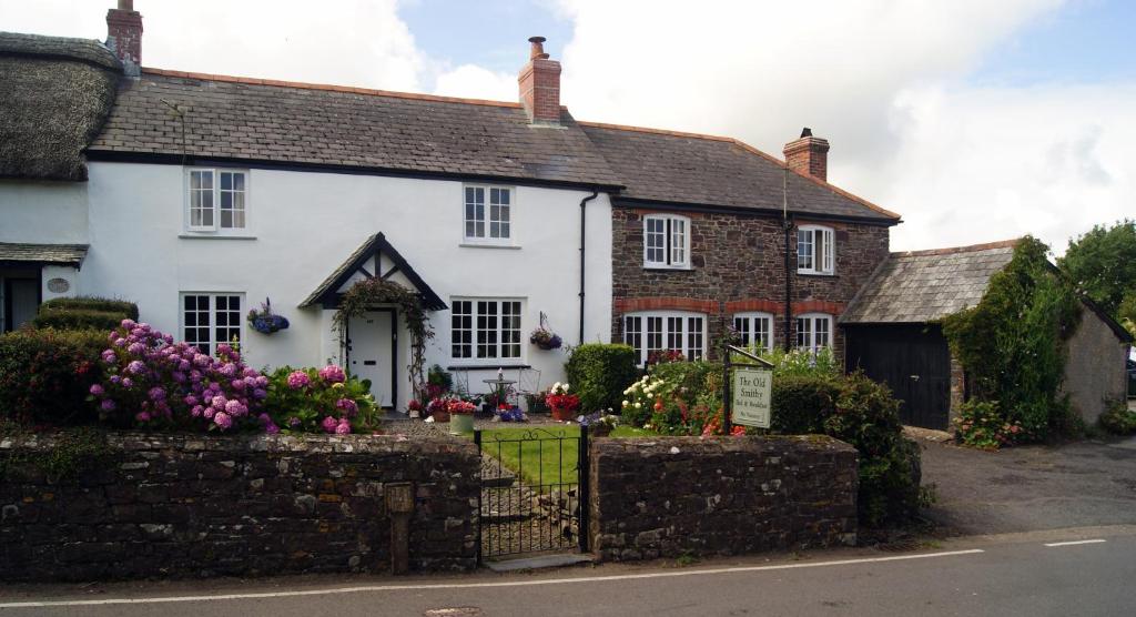 uma casa branca com flores à frente em The Old Smithy Bed & Breakfast em Clovelly