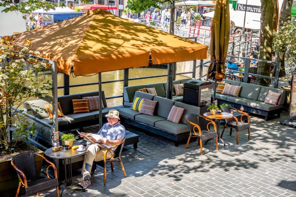 eine Person, die an einem Tisch unter einem Schirm sitzt in der Unterkunft Boutique Hotel Catshuis in Leeuwarden