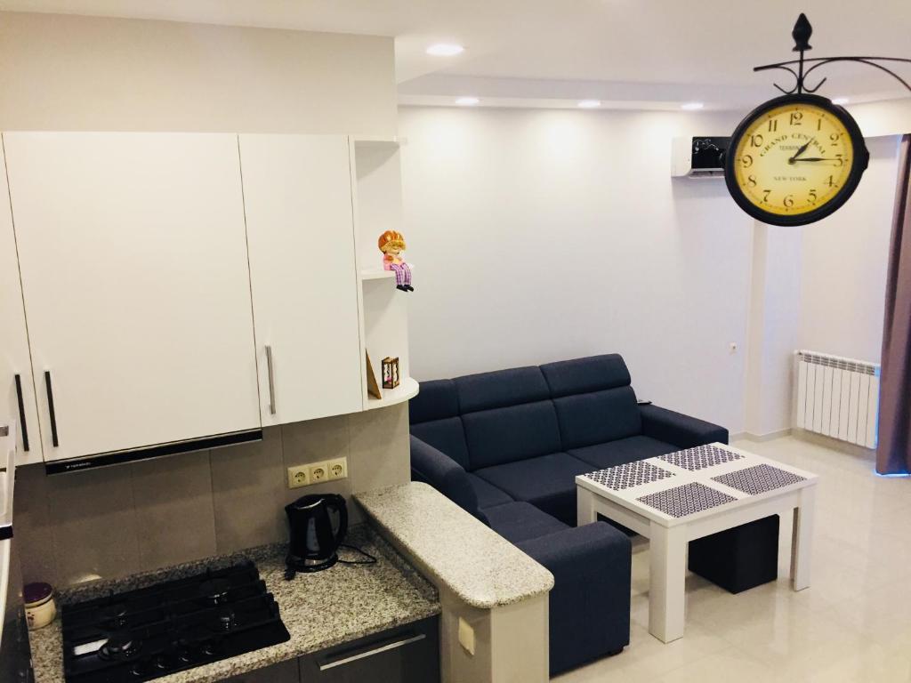 a living room with a couch and a clock on the wall at Belle Vue Apartment in Batumi