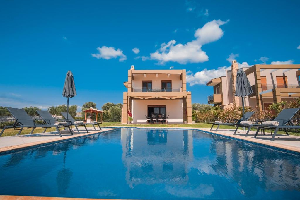 a villa with a swimming pool in front of a house at Saint Paul's Residences in Sani Beach