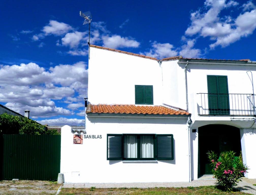 Casa blanca con persianas verdes y valla en Casa Rural San Blas, en Sanjuanejo