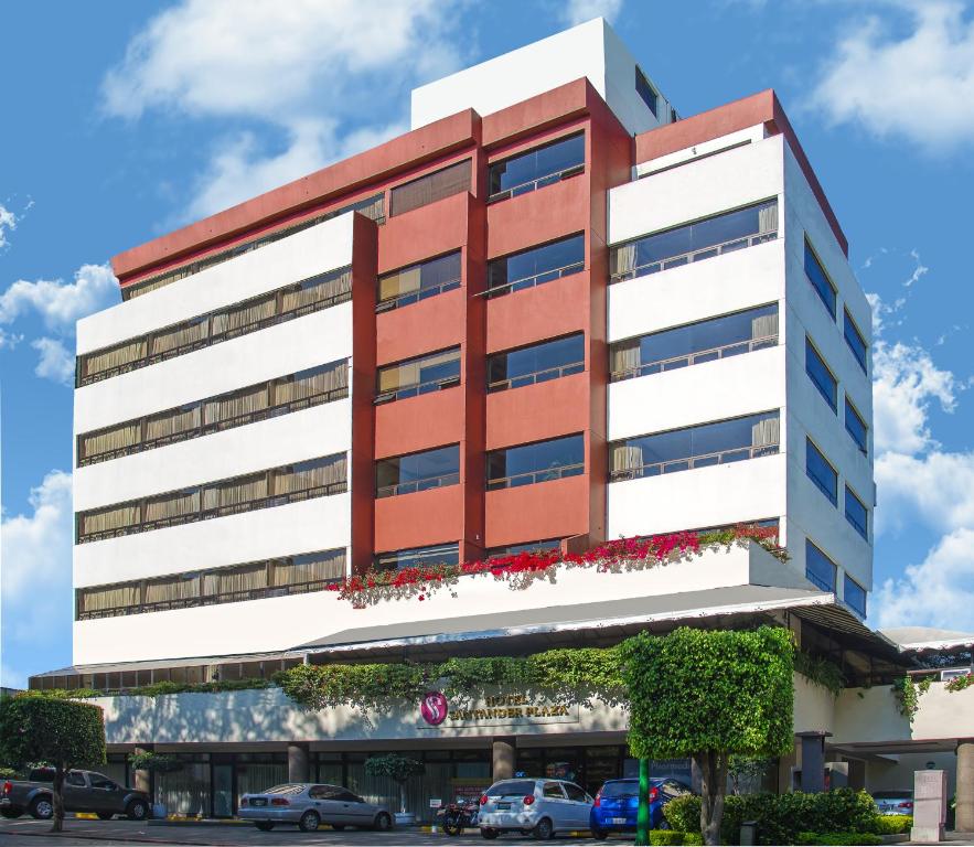 um edifício alto branco e vermelho com carros estacionados na frente em Hotel Santander Plaza em Guatemala