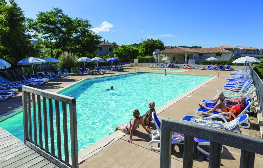 uma piscina num resort com pessoas sentadas em cadeiras de jardim em Résidence Odalys Acqua Linda em Poggio-Mezzana