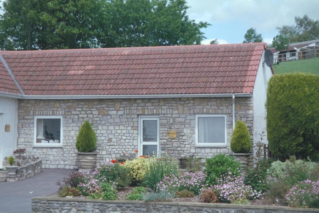 una pequeña casa de piedra con techo rojo en Greyfield Farm Cottages en Farmborough