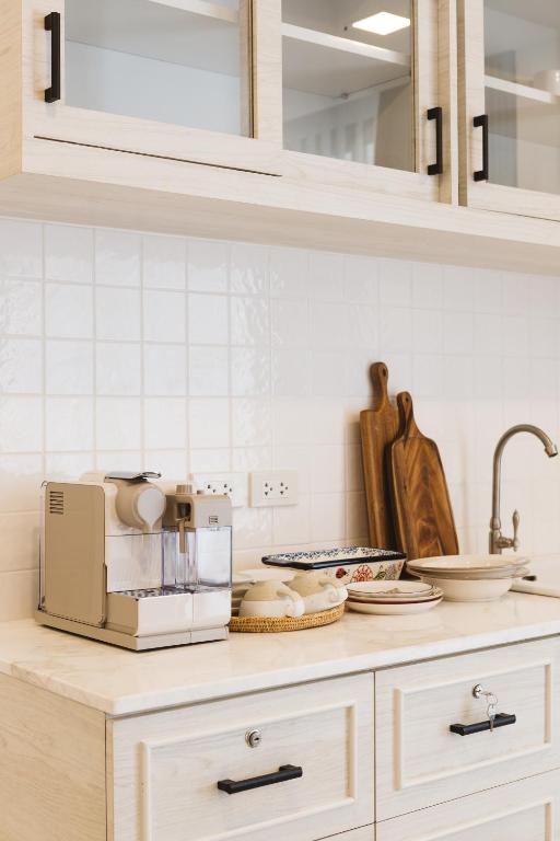 A compact kitchenette with a coffee machine, sink, dishes and overhead cupboards.