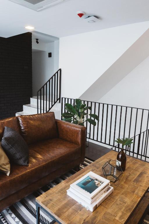 A leather sofa and wooden coffee table overlook an open stair railing in a modern lounge.