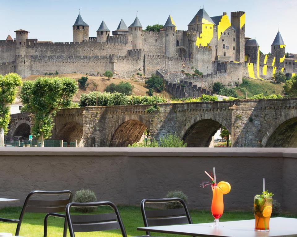 a view of a castle with a table and chairs at SOWELL HOTELS Les Chevaliers in Carcassonne