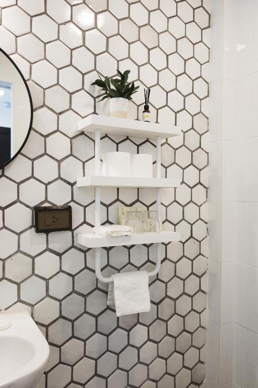 A bathroom feature wall with hexagonal tile, open shelves and toiletries.