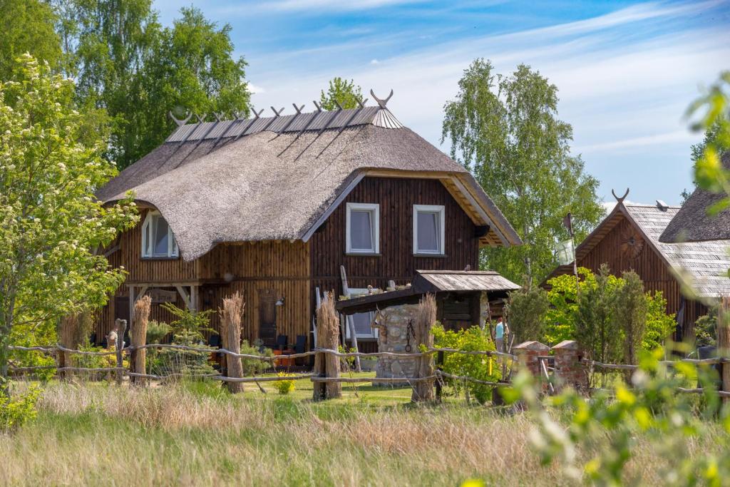 ein altes Holzhaus mit einem Strohdach in der Unterkunft Jurgi in Pape