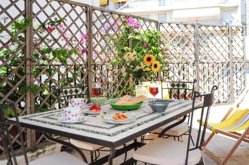 ニースにあるSuite ST Geneviève Five stars holiday houseの花の咲くバルコニーにテーブルと食べ物