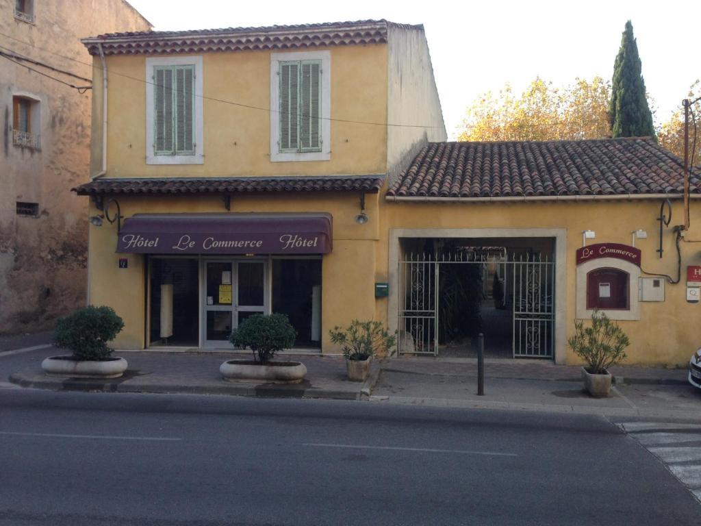 un bâtiment au coin d'une rue dans l'établissement Hôtel Restaurant Le Commerce, à Auriol