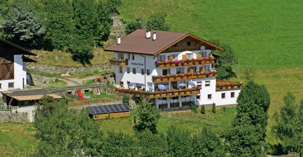 un grand bâtiment blanc avec un toit marron dans l'établissement Gasthof Walde, à Rifiano