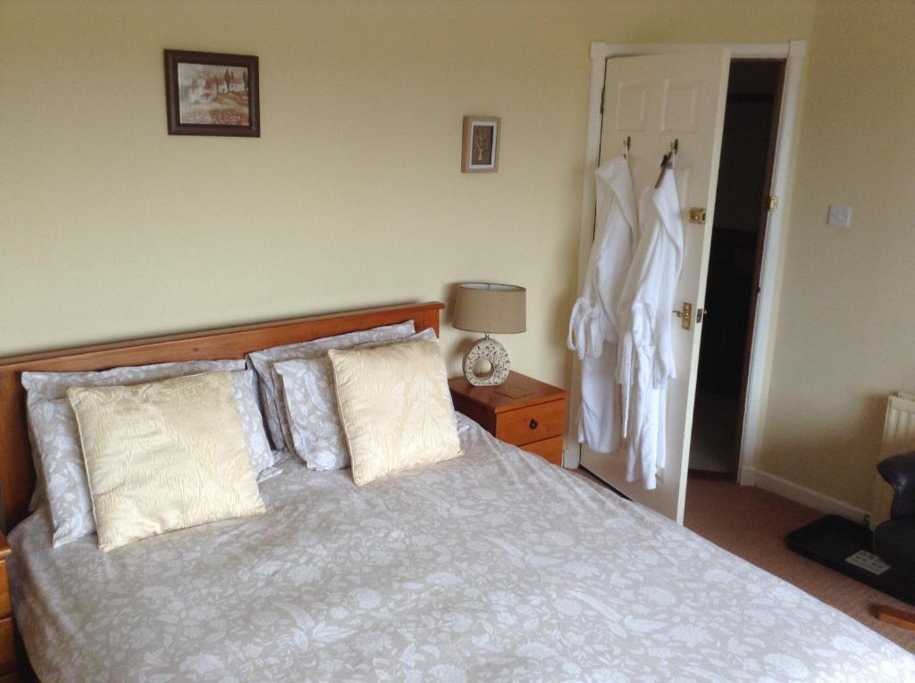een slaapkamer met een bed met kussens en een kast bij The Hawthorns B & B in Mey