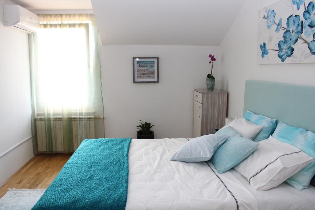 a bedroom with a large bed with blue and white pillows at Olad Riverview Townhouse in Sarajevo