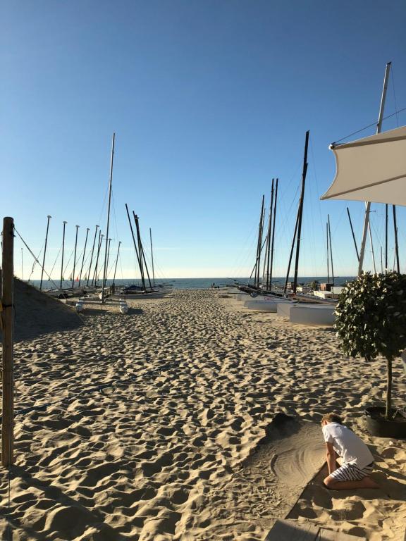 a man sitting on a sandy beach with an umbrella at Zeesymfonie Oostduinkerke in Koksijde