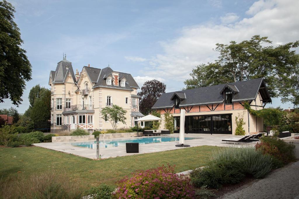 una casa grande con un patio con piscina en Manoir des Logis en Yvré-lʼÉvêque