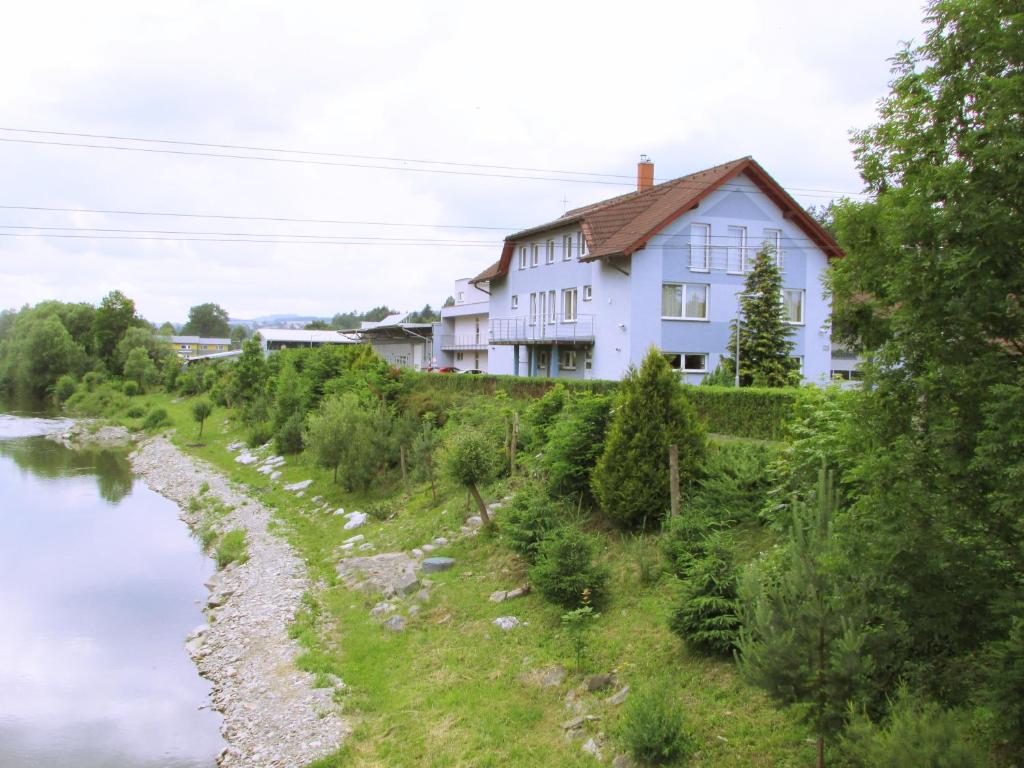 uma casa numa colina ao lado de um rio em Penzión KOVOX em Staškov