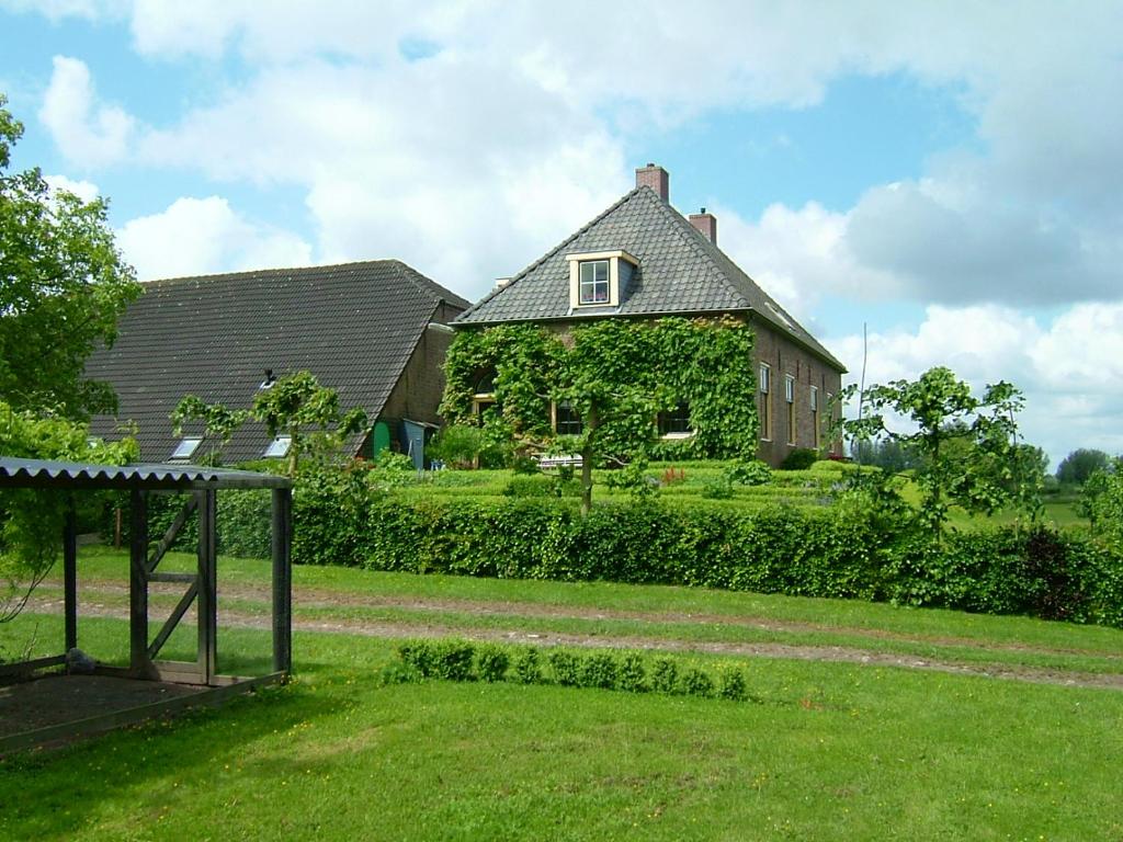 een groot huis met een tuin met een schommel bij Bed & Breakfast de Neust in Beesd