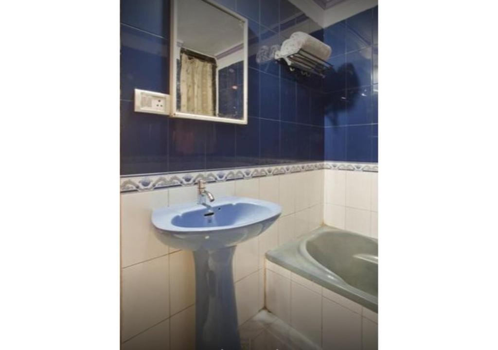 W łazience znajduje się umywalka, lustro i wanna. w obiekcie Balcony Rooms Overlooking the Main Market w mieście Pachmarhi