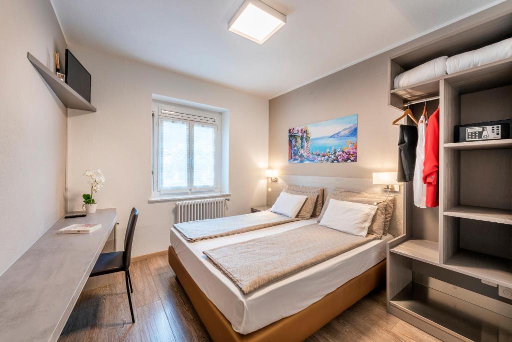 Habitación pequeña con cama y escritorio. en Albergo Ristorante Svizzero, en Capolago