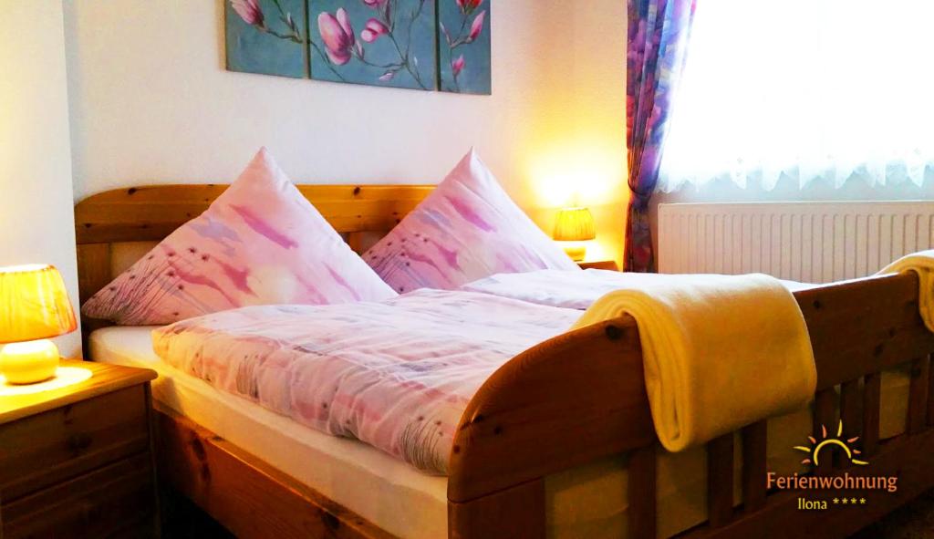 1 dormitorio con cama de madera con sábanas y almohadas rosas en Ferienwohnung Ilona, en Zweibrücken