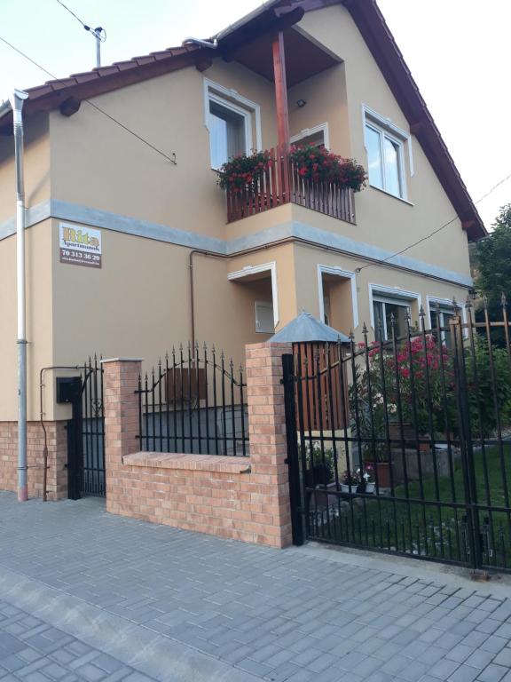 una casa con una valla negra y un edificio en Rita Apartman, en Bogács