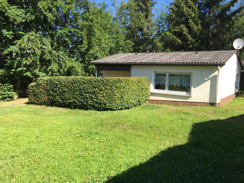 a house with a hedge in front of a yard at Ferienpark Wehrda GmbH in Wehrda